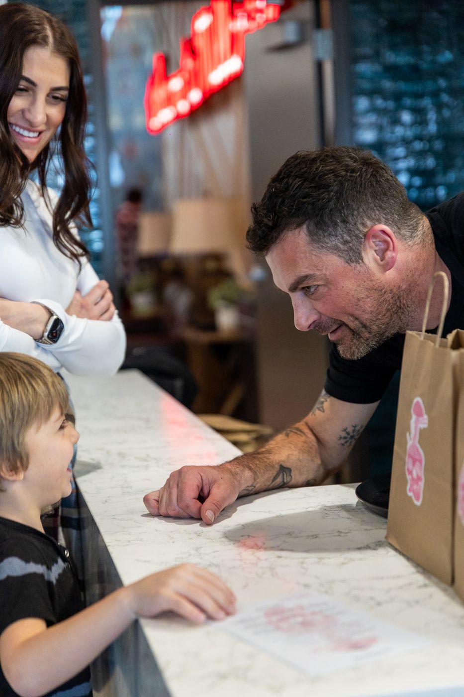 A chef chatting with a young guest across the counter