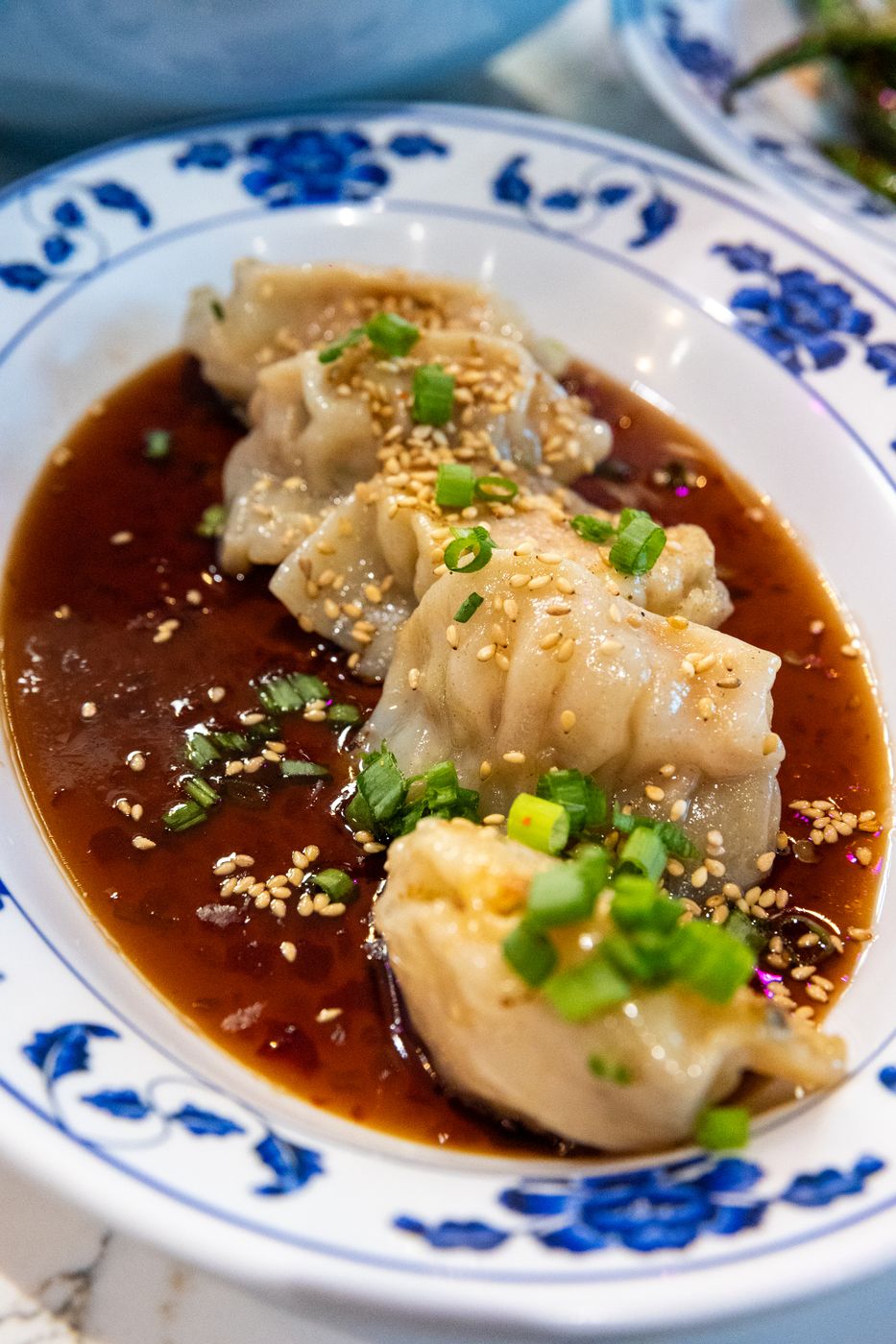 Pork potstickers in sweet chili sauce with scallion and sesame